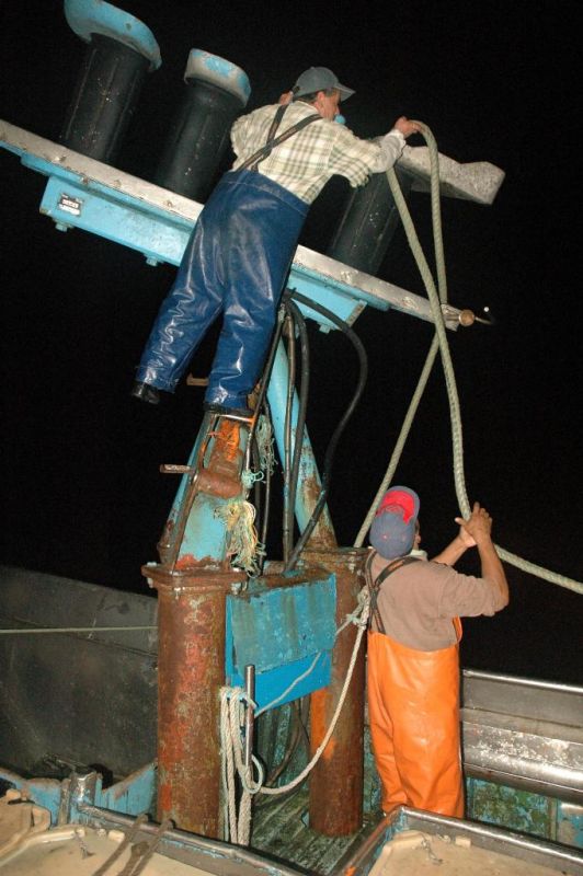 Dois pescadores organizam as cordas, que suportam as redes de pesca, antes de saírem para o mar.